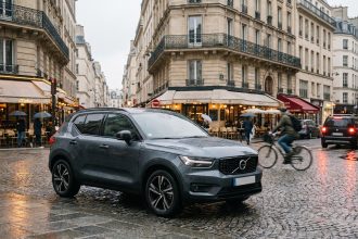 Petit SUV urbain compact garé dans une rue pavée européenne, vue en trois quarts avant, reflets sur les pavés mouillés, immeubles haussmanniens en arrière-plan